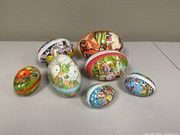 Group shot of all seven paper Easter eggs with varied sizes and colorful decorative scenes.