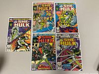 Photo showing five She-Hulk comic books with visible titles and cover illustrations