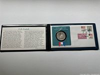 Opened portfolio showing one side with text about the U.S. Capitol and a protective casing for the coin and stamps.