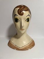 Front view of vintage painted millinery hat form showing face, hair, and decorative collar.