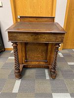 Front view of antique wooden writing desk showing leather top and twisted legs.
