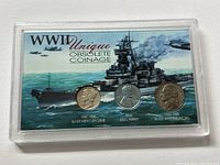 Front of the Plexiglas display case showing the three coins mounted on a colorful background illustration of a battleship and fighter planes, labeled with coin name and years minted.