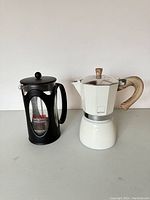 Both coffee makers shown side by side on flat surface against plain white background.