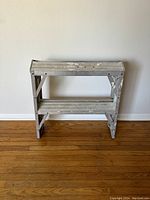 Side view of the metal two-step ladder showing structure and steps with paint splatters.