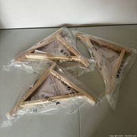Set of three wooden brackets still sealed in plastic bags with IKEA instructions visible inside.