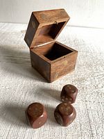 Photo of the wooden dice-shaped box with lid open and three small wooden dice with brass dots placed outside the box.