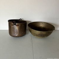Set of two vintage metal planters, one copper pot and one brass-plated bowl, showing surface wear and patina.