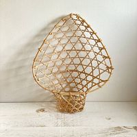 Front view of the vintage woven wicker hanging plant holder with visible fanned lattice back and basket base