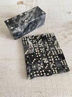 Photo showing domino tiles arranged flat with matching stone holder box placed on a light wooden surface.