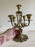 Brass ornate candelabra held in hand to show scale and detail