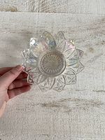 Top view of iridescent glass trinket dish showing star and geometric cut pattern and flower petal edges.