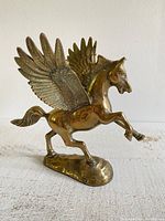 Side angle view of brass Pegasus statue showing wings and rearing pose
