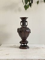 Front view of the vase showing its bulbous shape, pedestal base, and handles.