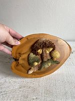 Close-up of the textured mushroom fiber artwork mounted on an oval wooden base showing detailed texture and natural wood grain.