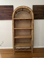 Front view of the wicker arched shelf showing its full height and arched top design with four shelves.