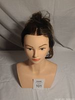 Front view of hair stylist's mannequin head showing facial features, styled synthetic hair, and torso bust.