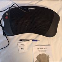 Homedics Shiatsu Body Massager with heat, placed on white surface alongside instruction manual and pen for scale, showing control buttons and product details.