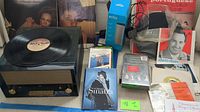 Vintage record player with multiple vinyl records displayed behind it including Donna Summer and Frank Sinatra.