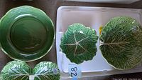 Solid green scalloped bowl and two cabbage leaf plates on white tray