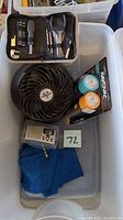 Photo of small fan, flashlights in packaging, digital accessory, and blue cloth in a bin