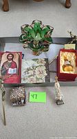 Overview of green glass vase with crosses on tray along with various religious items and decorative objects