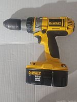 Full side view of yellow and black DeWalt cordless drill with visible model and battery markings.