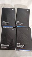 Four black Nike Performance Swimwear boxes displayed showing front branding.