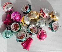 Top-down view of all 14 vintage glass Christmas ornaments showing different colors, shapes, and reflective surfaces with painted white, red, and gold details.