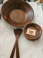 Top view of large walnut bowl, smaller bowl, and three wooden serving utensils