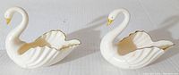 Pair of ivory porcelain swan figurines with gold accents viewed from side, both in good shape with no chips or cracks