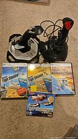 Full view of two wired flight simulator joysticks and four Microsoft Flight Simulator PC DVD games on carpeted floor.