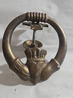 Front view of vintage brass Claddagh door knocker showing the detailed hands, crowned heart motif, and circular design