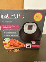 Front view of box for Instant Pot 6-in-1 Air Fryer Lid showing 6-quart capacity, program list, and image of lid and chicken wings.