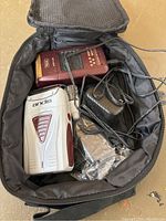 Photo of two electric shavers, power adapter, and accessories inside a black carrying case.