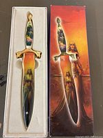 Full view of the decorative dagger in white display tray with the matching illustrated box beside it.