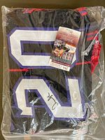 Photo of the signed jersey folded in plastic with visible number 20 and certificate inside packaging.