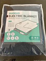 Photo of the packaged Duoduo Electric Blanket showing product details, model options, and features on front of packaging.