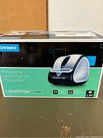Photo of the Dymo LabelWriter 450 box showing product image, branding, and features including compatibility for PC and Mac and printing speed of 51 labels per minute.
