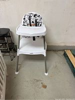 Front view of Evenflo baby high chair with star-patterned seat and white tray on concrete floor.