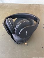 PowerLocus branded black wireless headphones resting on a black soft carrying case on a table.