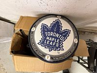 Overhead view of stool seat with Toronto Maple Leafs logo inside shipping box showing padded seat surface