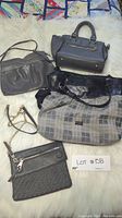 Lot of four grey purses on fabric background showing a variety of grey purses including a Tommy Hilfiger purse with plaid pattern and other styles