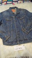 Front view of Levi's blue denim jean jacket laid flat showing button front, collar, chest pockets, and sleeves.