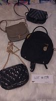 Four purses displayed on a white surface: black Valentino backpack, beige crossbody, black studded purse, and black quilted purse with chain strap.
