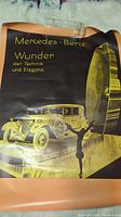 Photo showing the full poster with Mercedes-Benz vintage car and clock design along with German text.