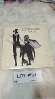 Front cover of Fleetwood Mac Rumours vinyl showing band members in monochrome with title, on white furry background with lot tag.