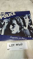 Front cover of The Police vinyl album Reggatta de Blanc laid on white furry fabric with lot number card.