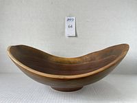 Side angle view of the oval wooden bowl showing its curved profile and smooth finish.