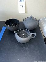 Top view of the black Wedgwood sugar bowl with lid, creamer, and 4-inch bowl showing matte finish exterior and glossy interiors.