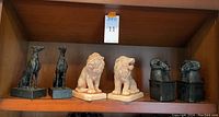 Shelf displaying all three pairs of bookends: metal dogs, ceramic lions, acrylic ram heads.